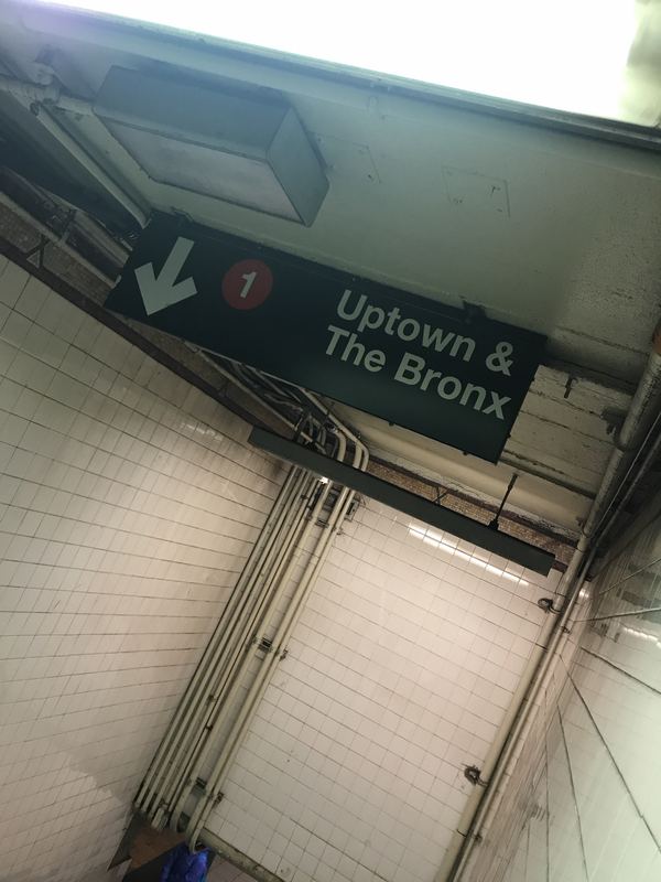 A subway sign pointing uptown, seen from below